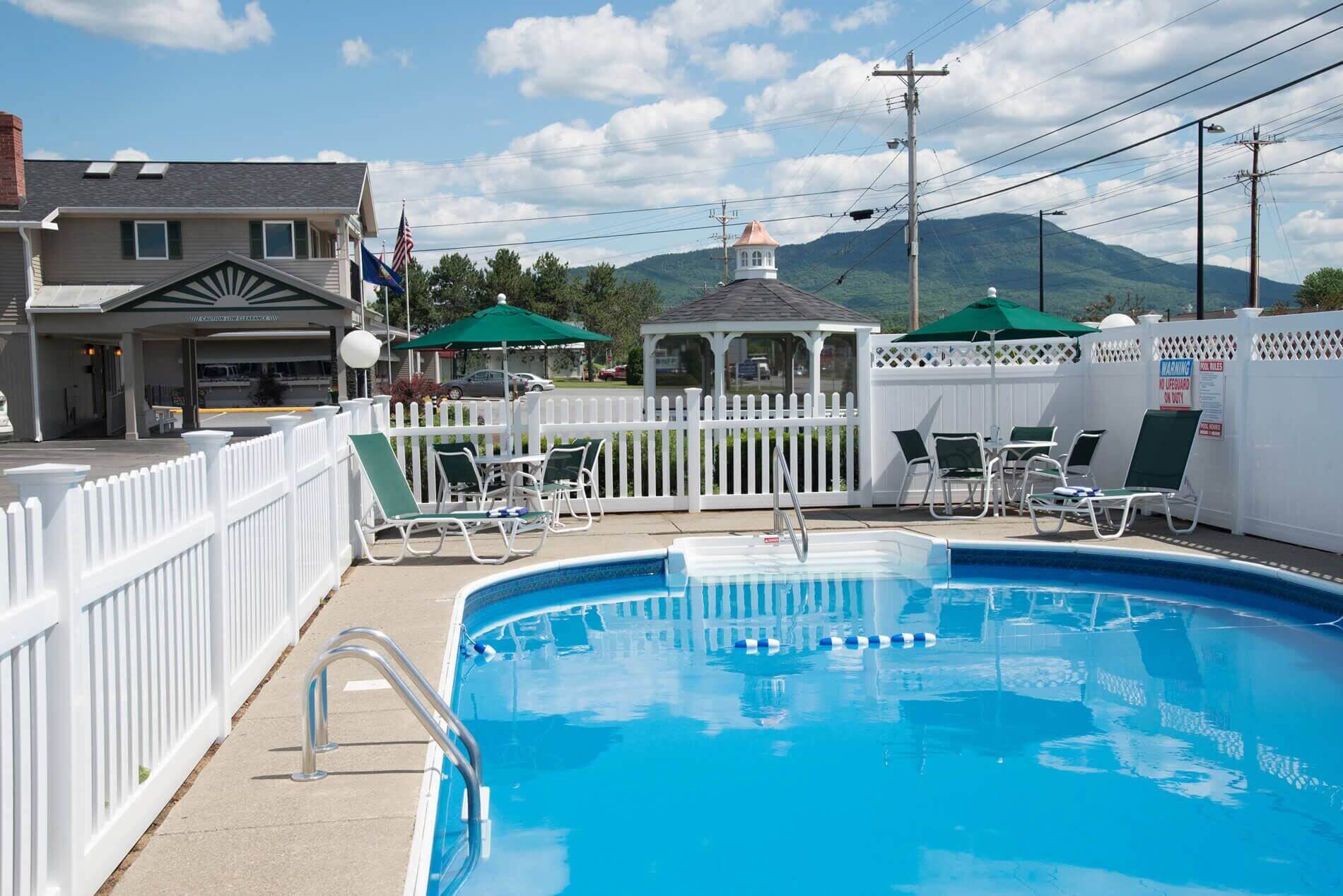 Inground pool inside fence with gazebo outside fenced area and mountains in the distance